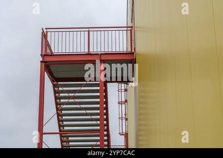 Escalier d'échappement rouge à l'extérieur de l'escalier sur le bâtiment industriel de mur jaune Banque D'Images