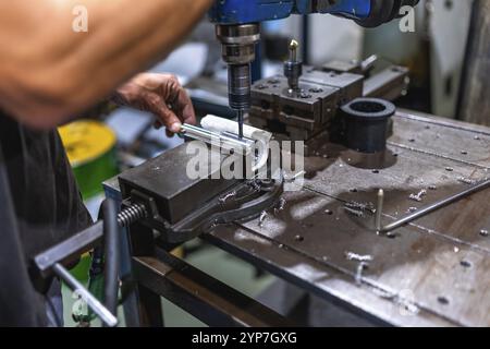 Gros plan d'un travailleur masculin travaillant à l'aide d'une machine de filetage dans un atelier métallique cnc Banque D'Images