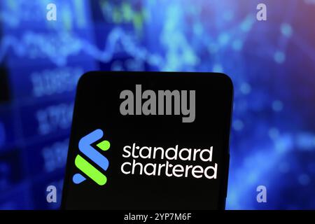 Dans cette illustration photo, le logo Standard Chartered est affiché sur l'écran d'un smartphone Banque D'Images