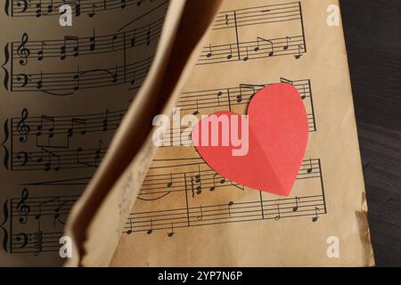 Coeur de papier et notes de musique sur fond noir, gros plan Banque D'Images