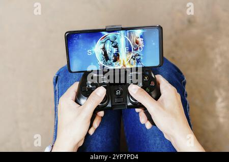Dans cette illustration photo, une personne jouant sur un joystick et le logo Starfield affiché sur un écran de smartphone Banque D'Images