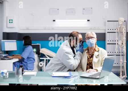 Le jeune médecin inspecte l'oreille du patient retraité féminin avec des soins professionnels, vérifiant l'infection à l'aide d'un équipement d'otologie. Médecin masculin tient l'otoscope et effectue le test auditif sur la femme retraitée. Banque D'Images