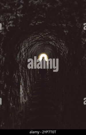Une personne marche dans un tunnel sombre et étroit vers la lumière, Dunedin, Nouvelle-Zélande, Océanie Banque D'Images