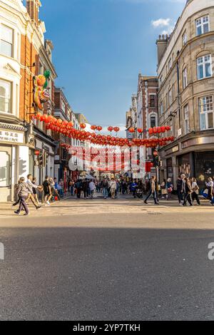 Londres, Royaume-Uni- 19 septembre 2024 : lanternes rouges suspendues au-dessus d'une rue animée du quartier chinois de Londres, remplies de gens et de vie urbaine. Banque D'Images