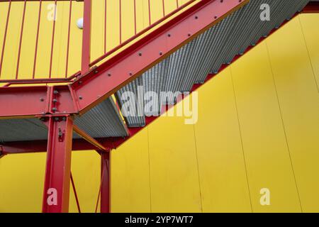 Escalier d'échappement rouge à l'extérieur de l'escalier sur le bâtiment industriel de mur jaune Banque D'Images