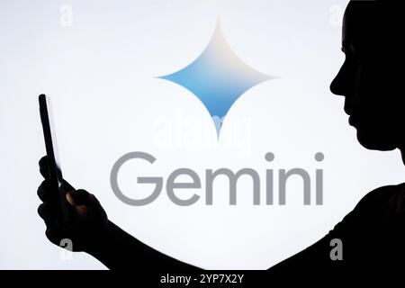 Dans cette illustration photo, la silhouette d'une femme tient un smartphone avec le logo Google Gemini en arrière-plan Banque D'Images