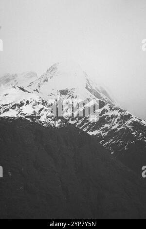 Image monochrome de sommets de montagne enneigés enveloppés de brume, Cattle Flat, Wanaka, Nouvelle-Zélande, Océanie Banque D'Images