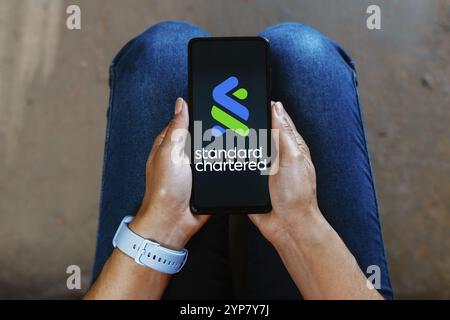 Dans cette illustration photo, le logo Standard Chartered est affiché sur l'écran d'un smartphone mobile Banque D'Images