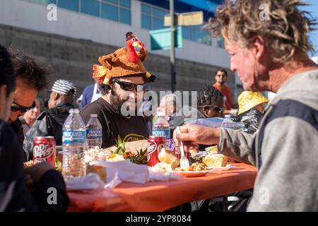 Los Angeles, États-Unis. 29 novembre 2024. Les gens apprécient leur repas de Thanksgiving. Des milliers de résidents de Skid Row et de sans-abri du centre-ville et au-delà ont été servis des dîners de Thanksgiving pendant la fête annuelle de la mission de Los Angeles. Crédit : SOPA images Limited/Alamy Live News Banque D'Images