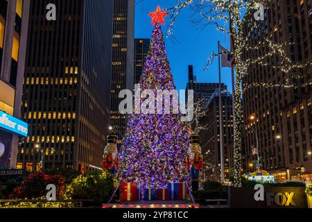 Un sapin de Noël vibrant orné de lumières colorées et d'une étoile rouge brillante au sommet, entouré de statues de casse-noix festives et de décorations des fêtes Banque D'Images