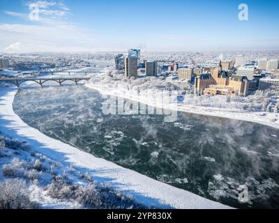 Une rivière enneigée avec un pont en arrière-plan. La ville est couverte de neige et la rivière est gelée Banque D'Images