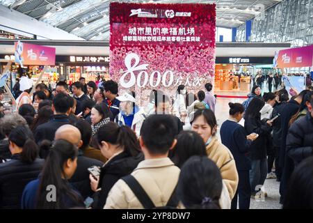 Dans le terminal de l'aéroport international de Chengdu Shuangliu, les passagers passent par le point d'enregistrement « le débit annuel de passagers du Chengdu International Aviation Hub dépasse 80 millions de passagers ». Chengdu, China.28th novembre 2024. Pour la première fois, le débit annuel de passagers du Chengdu International Aviation Hub a dépassé 80 millions. Chengdu est également devenue la troisième ville de Chine continentale avec un volume annuel de passagers dépassant les 80 millions, après Pékin et Shanghai, le 28 novembre 2024. Crédit : Zhang Lang/China News Service/Alamy Live News Banque D'Images