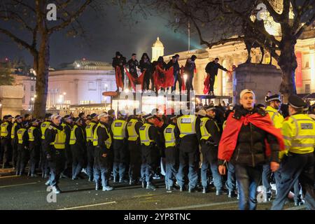 Londres, Royaume-Uni. 28 novembre 2024. Les gens se tiennent debout sur un toit d'un abri de bus agitant des drapeaux albanais alors que la communauté célèbre le jour de l'indépendance de la nation dans et autour de Trafalgar Square. La police a imposé une ordonnance de dispersion en vertu de l'article 35 plus tard dans la soirée après que la circulation routière ait été bloquée. Crédit : onzième heure photographie/Alamy Live News Banque D'Images