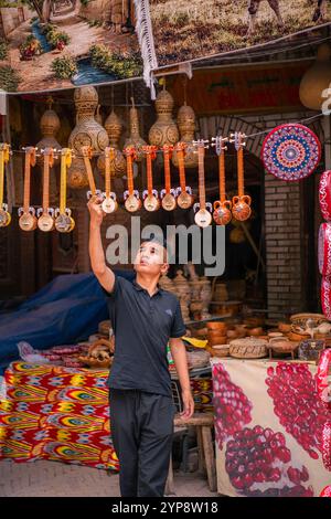 Kashgar, Chine - 17 JUILLET 2022 : homme ouïghour dans son magasin d'instruments de musique sur un marché local dans le vieux Kashgar Banque D'Images