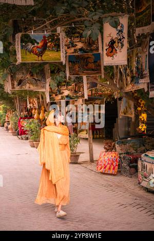 Kashgar, Chine - 17 JUILLET 2022 : une fille à côté du magasin vendant des tapis et des instruments de musique dans la rue de la ville antique de Kashgar, Xinjiang, Chine Banque D'Images