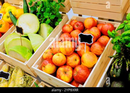 Les pommes fraîchement récoltées et les légumes sont soigneusement exposés dans des caisses en bois au marché agricole local animé Banque D'Images