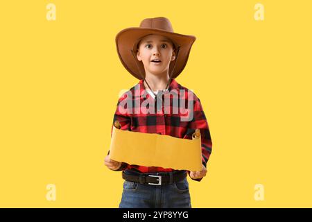 Mignon petit cow-boy avec carte au trésor sur fond jaune Banque D'Images