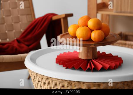 Stand avec des mandarines sur la table dans le salon décoré pour le nouvel an chinois, gros plan Banque D'Images