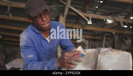 Vue de face d'un batteur de panneau mâle africain dans un atelier township, ponçage et préparation de la surface de Banque D'Images