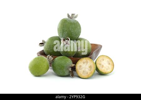 Un bol en bois rempli de feijoas vertes fraîches, certaines entières et certaines tranchées, soulignant leur couleur vibrante et leur texture. Idéal pour mettre en valeur le pr frais Banque D'Images