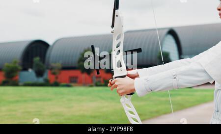 Femme, mains et préparer l'arc pour la formation de tir à l'arc à l'académie, exercice en plein air et viser. Personne féminine, défi de tir et terrain pour la compétition Banque D'Images