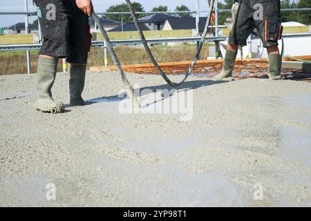 Ouvriers remplissant le sol du deuxième étage avec le béton, le noyau et le bâtiment de construction de coquille Banque D'Images