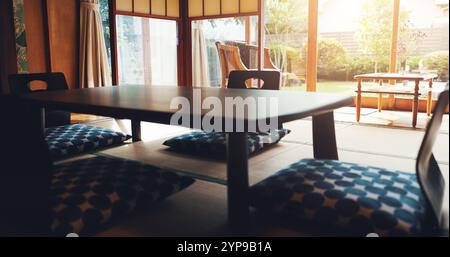 Salle à manger, table et décoration intérieure japonaise avec chaise de sol avec culture asiatique pour la pleine conscience dans la maison. Rétro, pièce vide et minimaliste avec bois bas Banque D'Images