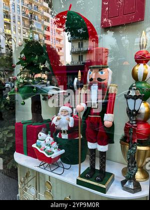 Cette photo verticale capture une vitrine hivernale festive qui respire la joie des fêtes. Dominant la scène est une grande robe de figurine casse-noisette Banque D'Images