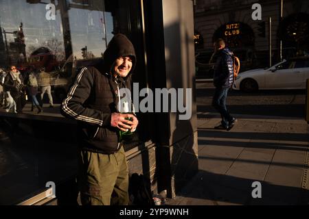 Homme sans-abri tenant une bouteille de Stella Artois le long de Piccadilly, la rue la plus riche de Londres où riches et pauvres se côtoient, Angleterre, Royaume-Uni Banque D'Images