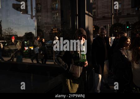 Homme sans-abri tenant une bouteille de Stella Artois le long de Piccadilly, la rue la plus riche de Londres où riches et pauvres se côtoient, Angleterre, Royaume-Uni Banque D'Images