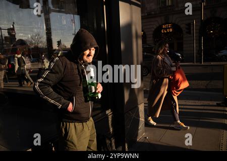 Homme sans-abri tenant une bouteille de Stella Artois le long de Piccadilly, la rue la plus riche de Londres où riches et pauvres se côtoient, Angleterre, Royaume-Uni Banque D'Images