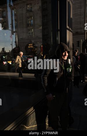 Homme sans-abri tenant une bouteille de Stella Artois le long de Piccadilly, la rue la plus riche de Londres où riches et pauvres se côtoient, Angleterre, Royaume-Uni Banque D'Images