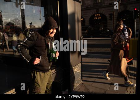 Homme sans-abri tenant une bouteille de Stella Artois le long de Piccadilly, la rue la plus riche de Londres où riches et pauvres se côtoient, Angleterre, Royaume-Uni Banque D'Images