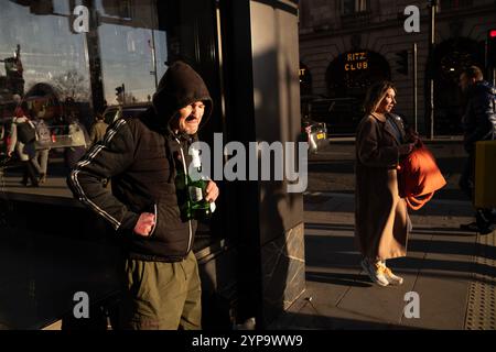 Homme sans-abri tenant une bouteille de Stella Artois le long de Piccadilly, la rue la plus riche de Londres où riches et pauvres se côtoient, Angleterre, Royaume-Uni Banque D'Images