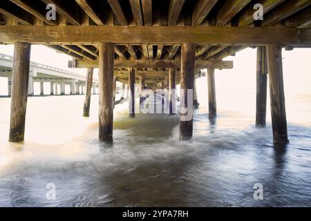 Gentel fait des vagues sous une jetée en bois. Banque D'Images