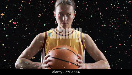 Image de confettis tombant sur une joueuse de basket-ball féminine caucasienne sur fond noir Banque D'Images