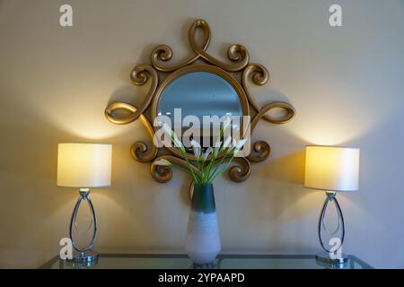 Un miroir doré et blanc avec un vase de fleurs blanches devant lui Banque D'Images