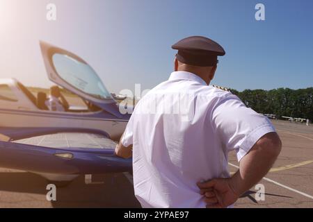 Le pilote se tient près d'un avion à moteur léger appuyé sur l'aile. Banque D'Images