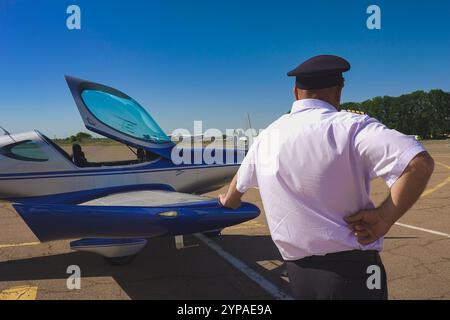 Le pilote se tient près d'un avion à moteur léger appuyé sur l'aile. Banque D'Images