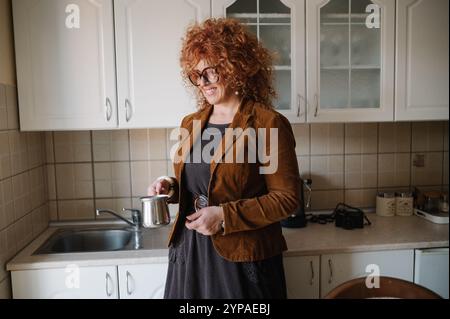 Souriante femme d'affaires d'âge moyen préparant le café à la maison. Banque D'Images