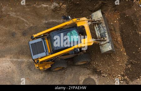 Un puissant bulldozer ou chargeur déplace la terre sur le chantier de construction. Un engin de terrassement est en train de niveler le chantier. Équipement lourd de construction pour e Banque D'Images
