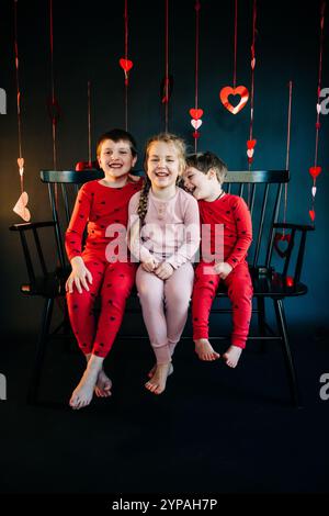 Trois enfants joyeux en pyjama avec des décorations de coeur de Saint-Valentin Banque D'Images