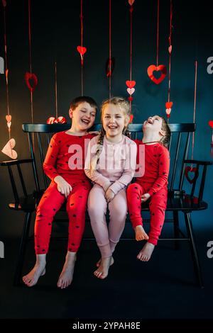 Trois enfants riant avec des décorations de Saint-Valentin sur le thème du cœur Banque D'Images