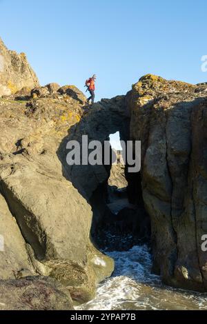 Un marcheur au sommet d'une arche rocheuse naturelle près de la célèbre Elie Chain Walk, Elie, Fife, Écosse Banque D'Images