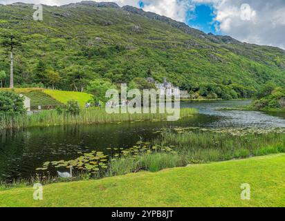 Une scène tranquille au bord du lac avec une végétation luxuriante, un château niché dans les montagnes, et des eaux calmes reflétant la beauté de la nature. Parfait pour paisible Banque D'Images