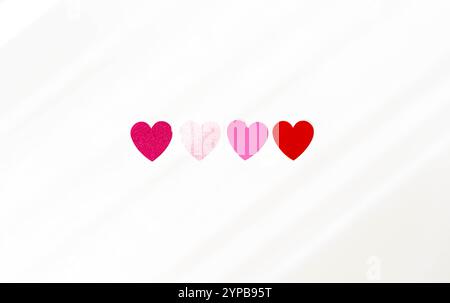 Une collection de formes de coeur rouges, roses et oranges de différentes couleurs disposées sur un fond clair. Vue de dessus. Copier l'espace Banque D'Images