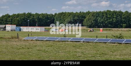 Pays-Bas chantier pour une ferme d'énergie solaire en plein soleil à côté d'une autoroute, avec des arbres et un ciel bleu. Plante à petite échelle dans la forground. Banque D'Images