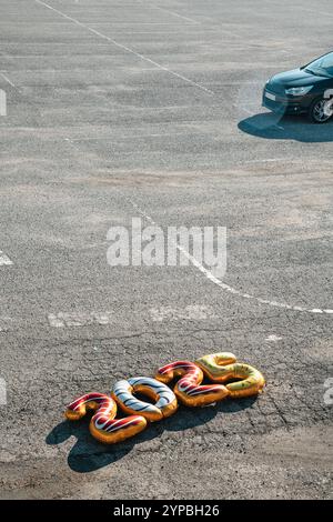 quatre ballons en forme de numéro de feuille de différentes couleurs formant le numéro 2025, comme la nouvelle année, sur l'asphalte d'un parking désert, sur un da ensoleillé Banque D'Images