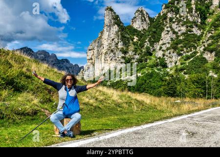 Touriste latino-américain d'âge moyen, souriant, les bras levés dans la joie, se reposant assis pendant une randonnée en montagne. Banque D'Images