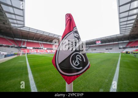 Symbolbild für den SC Freiburg, Eckfahne mit Vereinslogo im Fokus, im Hintergrund das Stadion mit roten Sitzreihen und dem Schriftzug ãSC FreiburgÒ, grüner, gepflegter Rasen mit klaren weißen Spielfeldmarkierungen, leere Tribünen und ruhige Atmosphäre vor Spielbeginn, repräsentiert Heimat, Professionalität und die Verbindung zwischen Verein und Stadion für Vereinsidentität Fußballkultur dans le fond le stade avec des rangées rouges de sièges et le lettrage ÒSC FreiburgÓ, vert, bien Banque D'Images